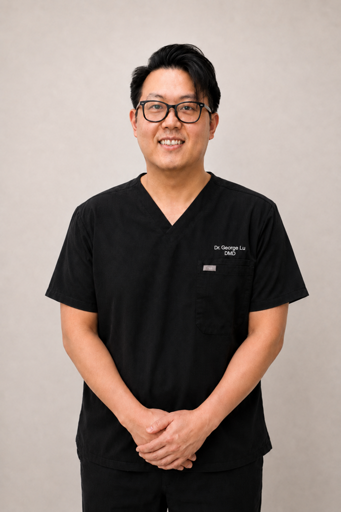 Portrait of Dr. George Lu, DMD, in black scrubs, smiling with hands clasped in front.